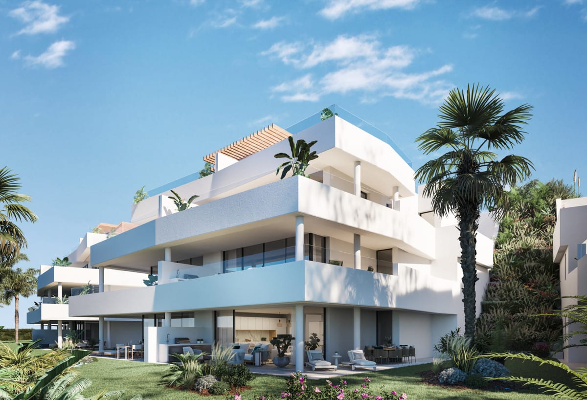 Project visualisation of MIRADOR DE ESTEPONA HILLS with a corner view of a white building, cantilevered balconies, round columns, palm trees and lush planting.