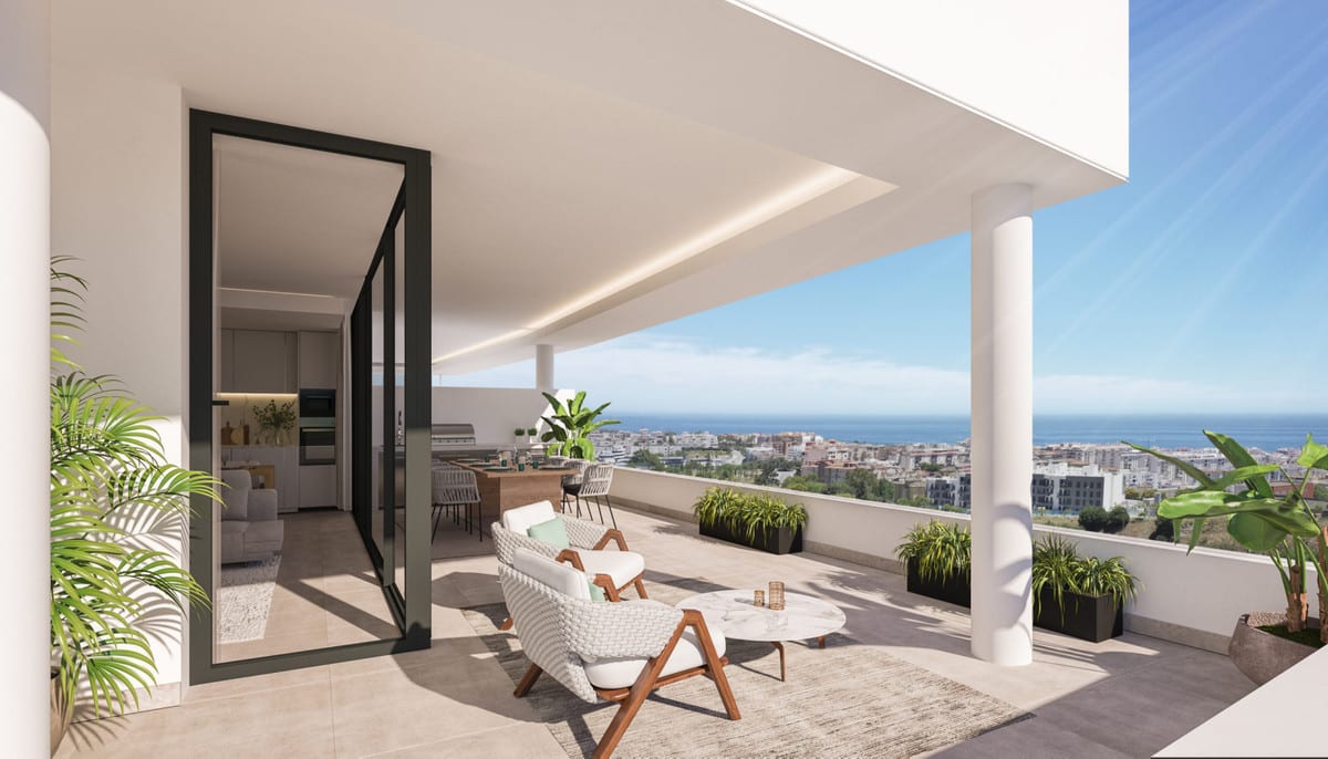 Project visualisation of the terrace at MIRADOR DE ESTEPONA HILLS with tiled flooring, white columns, a black steel door frame, woven seating, planters and views over the surrounding buildings towards the sea.
