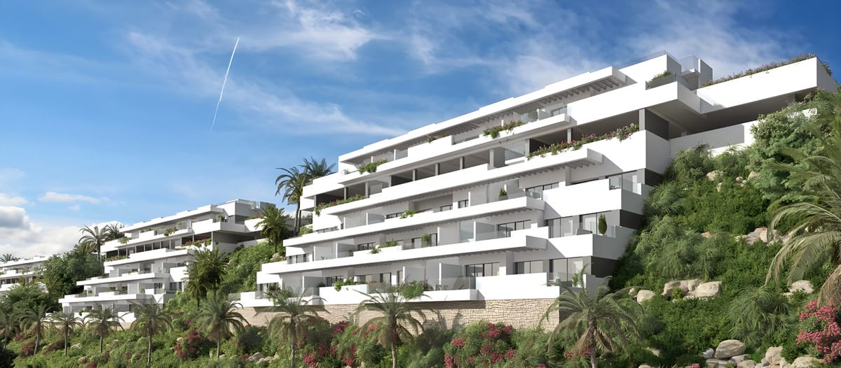 Project visualisation of NAVIGOLF SUITES 2 featuring white terraced buildings, planted balconies, palm trees, rocks and flowering shrubs on a green hillside.