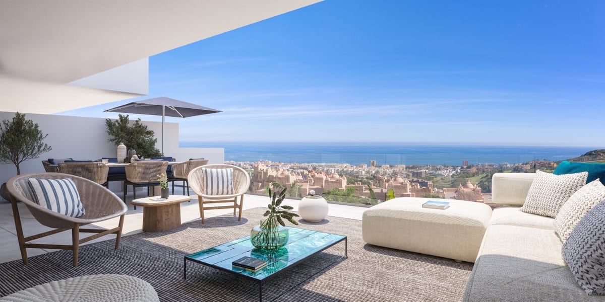 Project visualisation of the terrace at PURE SUN II with a white sofa, two woven armchairs, a glass coffee table and a dining table beneath a parasol.