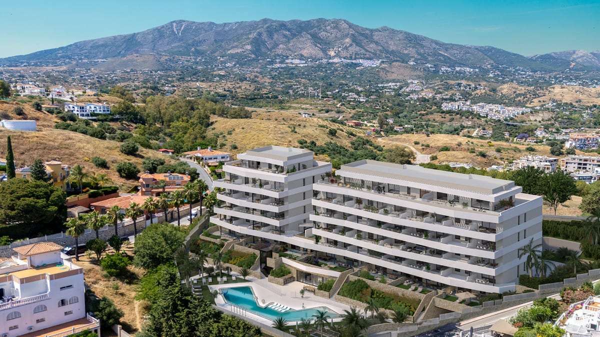 Aerial view with development visualisation of RESIDENCIAL COTO HOMES: a modern white building with terraces and a swimming pool, surrounded by a hilly landscape with existing buildings.