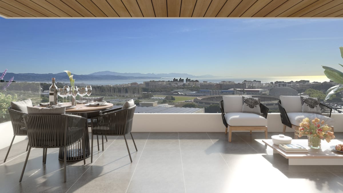 Project visualisation of RESIDENCIAL LIVING GARDENS featuring a covered terrace, round dining table with woven chairs, lounge chairs with a coffee table, and views of buildings, mountains and water.