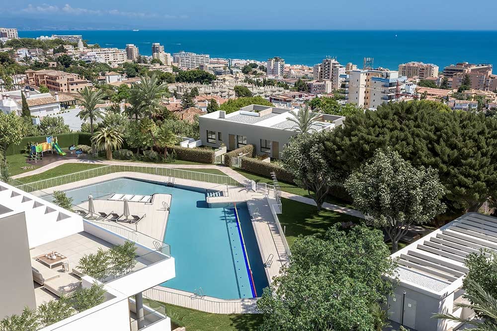 Project visualisation of RESIDENCIAL PACARAIMA - ADOSADO with two swimming pools, sun loungers with parasols, green trees and the sea on the horizon.