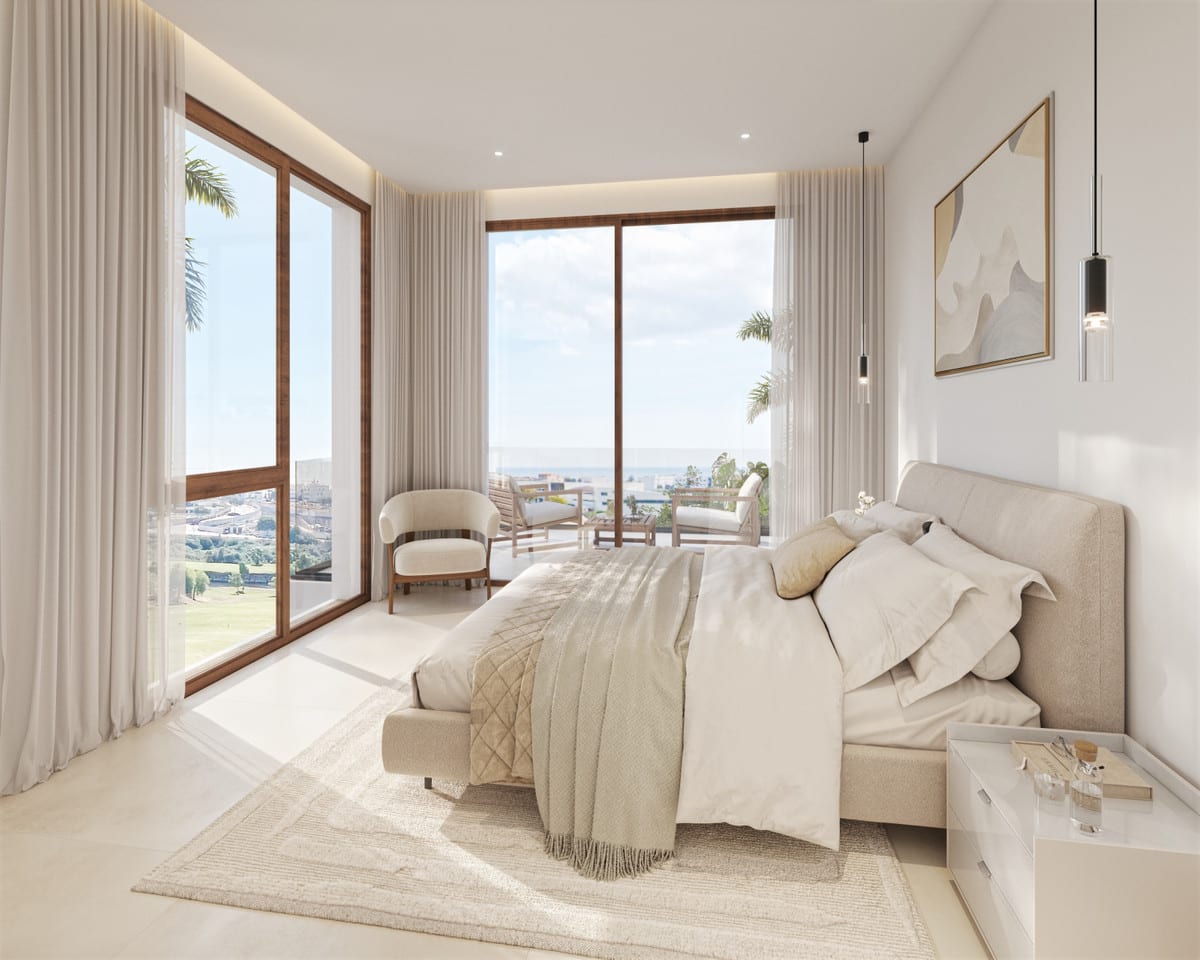 Interior visualisation of SWING AND SEA VILLAS featuring a light bedroom, an upholstered double bed, round armchair, rug, pendant lights and two large sliding doors with wooden frames opening onto a terrace with chairs and a side table.