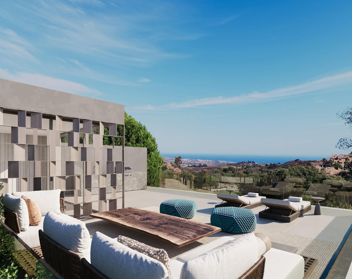 Project visualisation of TERRA NOVA HILLS featuring a terrace with a rattan lounge sofa, wooden coffee table, turquoise pouffes, sun loungers, a glass balustrade and open views across hills and coastline.