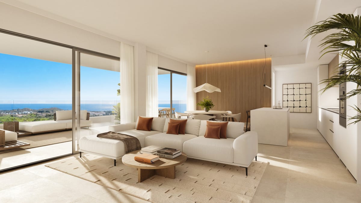 Project visualisation of the open-plan living area at THE EAGLE RESIDENCES with a white corner sofa, terracotta cushions, round coffee table, dining area, wooden wall panel, kitchen with island and sliding glass doors with a rendered sea horizon in the background.