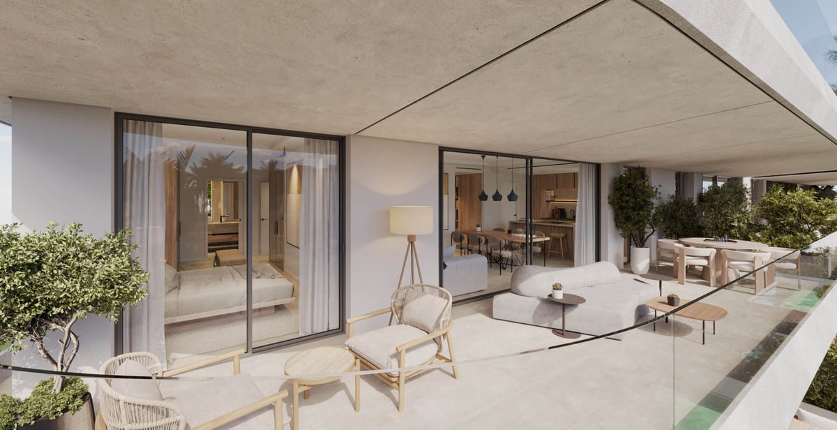 Project visualisation of THE PALMS AT ESTEPONA featuring a spacious covered terrace, concrete canopy, glass balustrade, lounge seating, a small side table with chairs and sliding glass doors to the bedroom and kitchen.