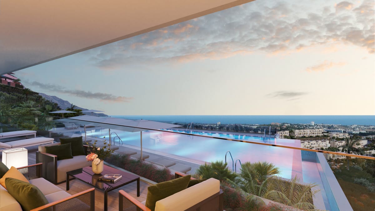 Project visualisation of TIARA with a covered terrace, a lounge area with a sofa, armchairs and a floor lamp, a glass balustrade and a wide illuminated swimming pool, with buildings and water on the horizon.