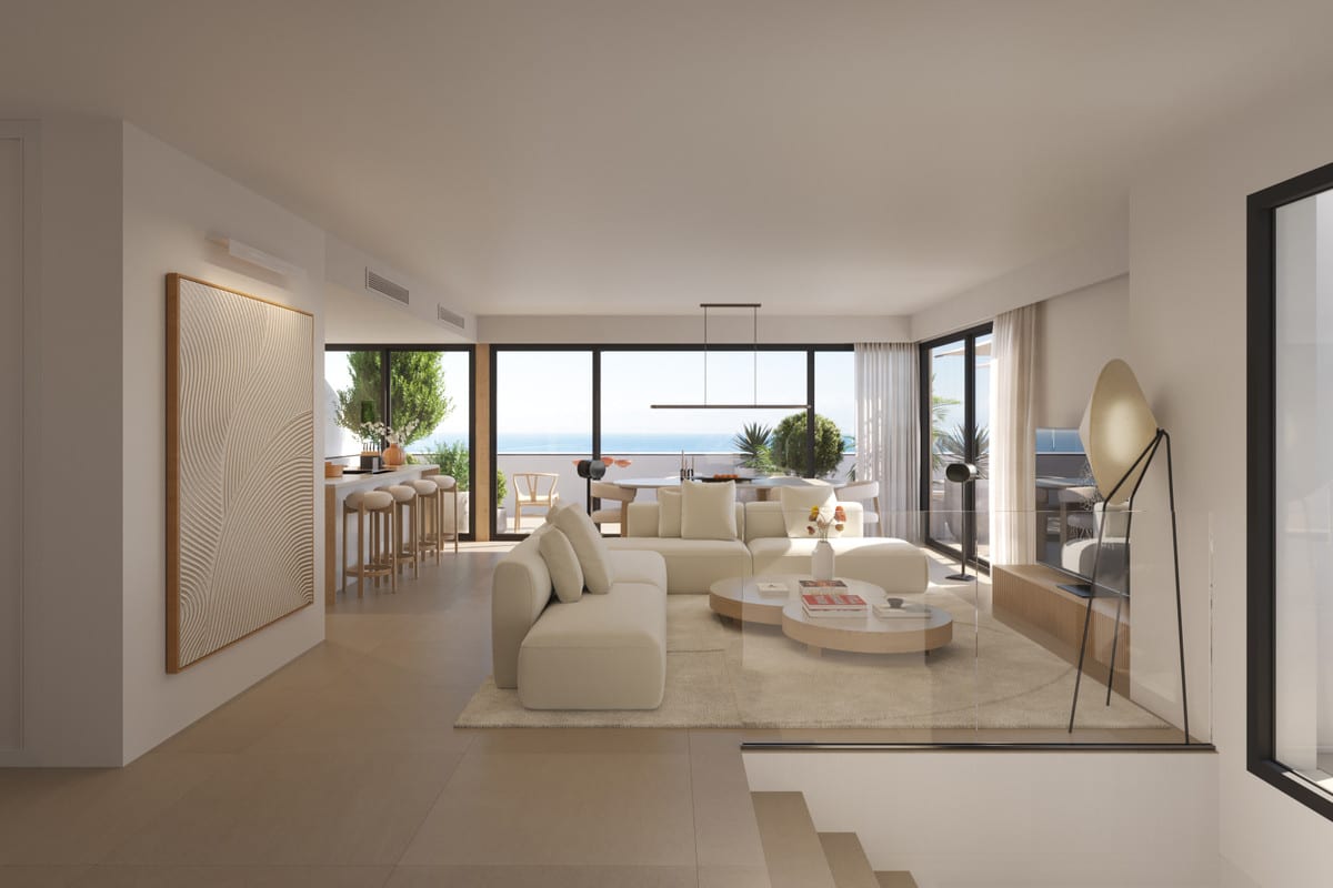 Rendered interior view of TORRE BIZNAGA with a cream corner sofa, two coffee tables, large black-framed windows with sea views and a visible kitchen area in the background.