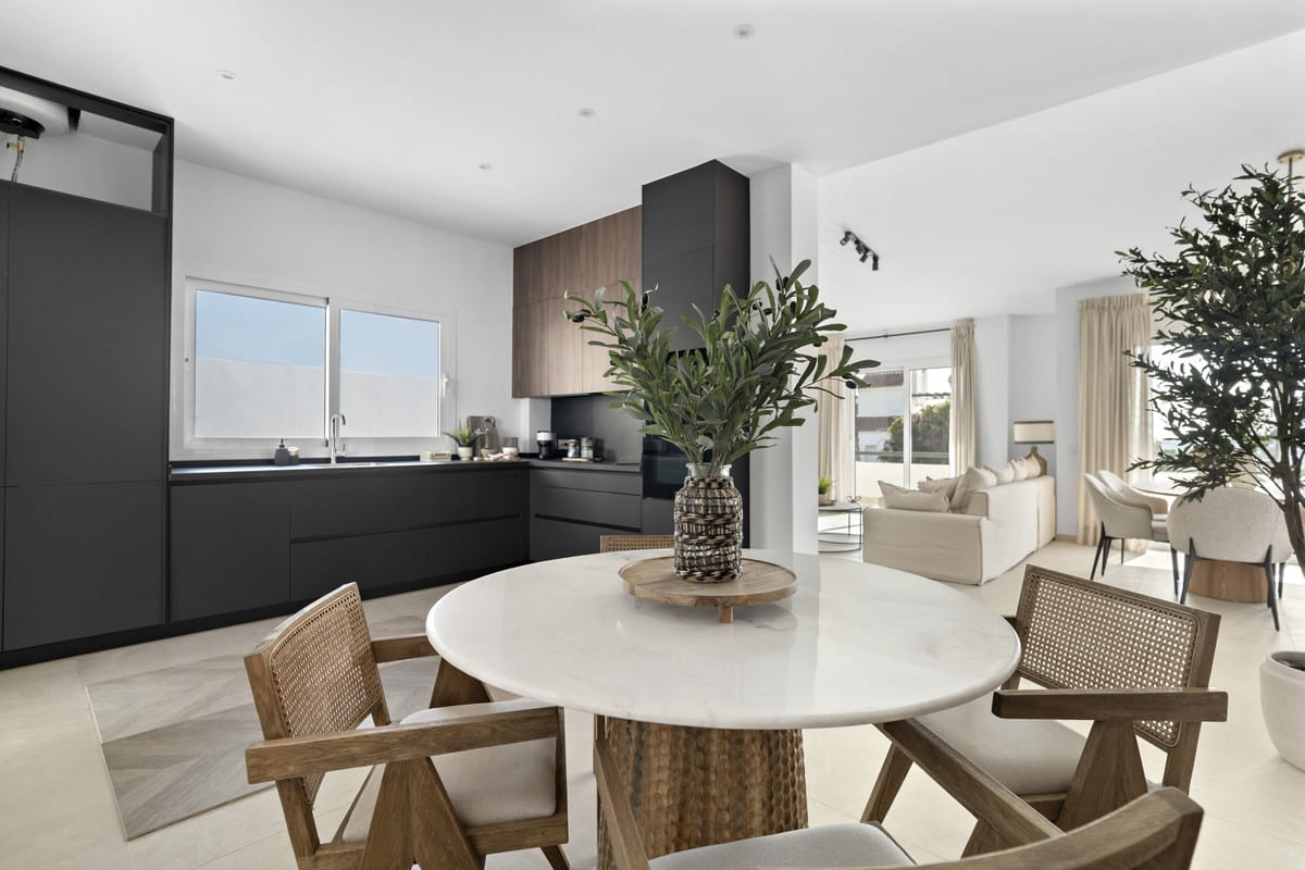 URBANIZACIÓN OLIMPO open-plan kitchen with dark and wood-toned cabinets, a round table with a white marble top and wooden chairs with woven backrests.