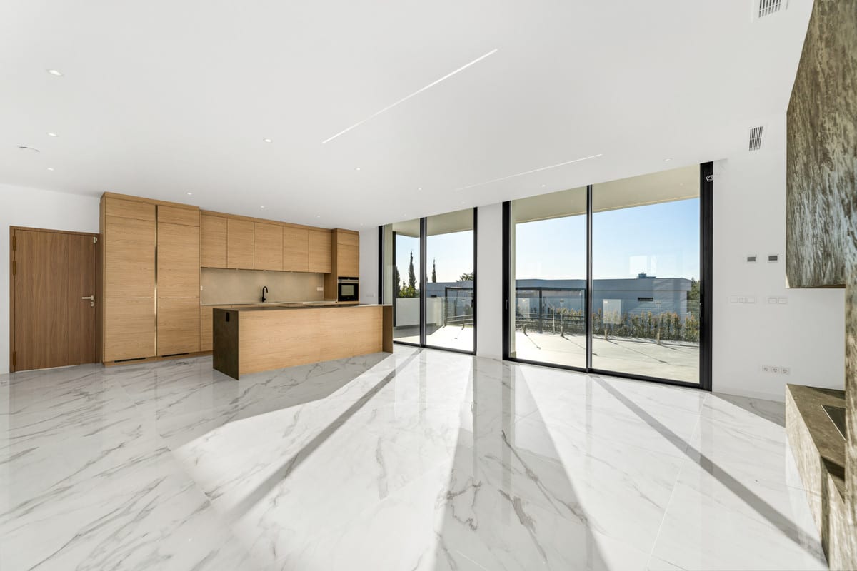 The open living space combines wooden kitchen cabinetry with a large island, sliding glass doors and a polished floor.