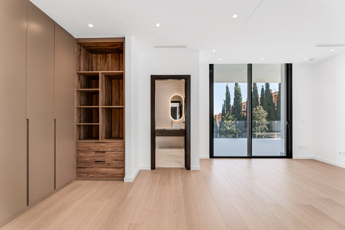 A quiet room with light wooden flooring, fitted wardrobes and a doorway to an adjoining bathroom.