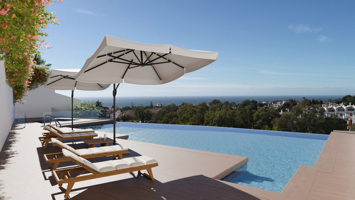 Designbillede af en lang blå pool ved en flisebelagt solterrasse med træliggestole og hvide parasoller; planter, bygninger og hav ses bag kanten.