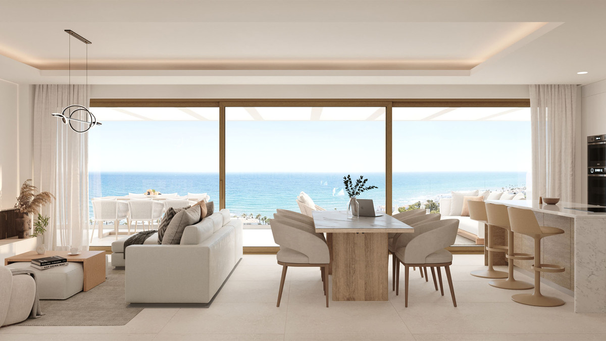 Interiørvisualisering med lys siddegruppe, spisebord og åbent køkken, forbundet med en terrasse gennem brede glasskydedøre med havet i baggrunden.