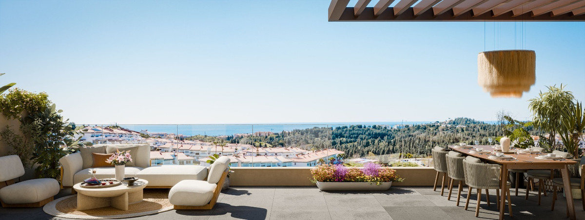 Panoramisk terrassevisualisering med lounge til venstre, spisebord under en træpergola til højre og lave plantekasser langs kanten, med havet i horisonten.