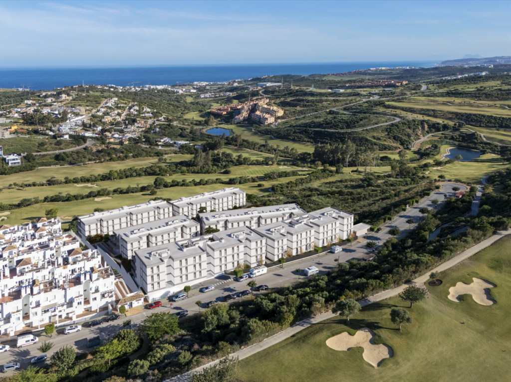 Skråt luftfoto fra præsentationen af ETHERNA HOMES I med hvide boligblokke, omkringliggende veje, grønne områder og kystlinjen i baggrunden.