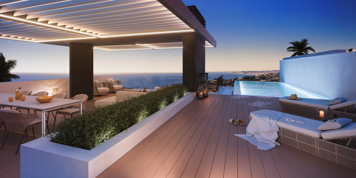 Designbillede af en terrasse under lameltag med spisebord, lang plantekasse og liggestole ved en oplyst pool; hav og kystbebyggelse ses i baggrunden.