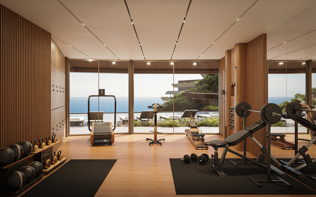 Visualisering af et fitnessrum med træbeklædning, vægte, træningsbænk og konditionsmaskiner samt store glaspartier mod en terrasse og havet.