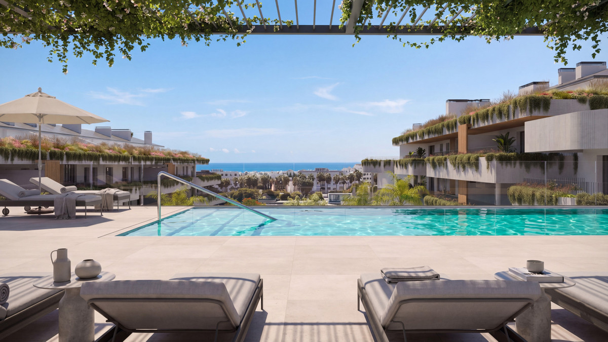 Visualisering af THE GROVEs fælles udendørs pool med terrasse, liggestole og omkringliggende boligbygninger; kystlinjen i baggrunden bekræfter ikke havudsigt fra en bestemt lejlighed.