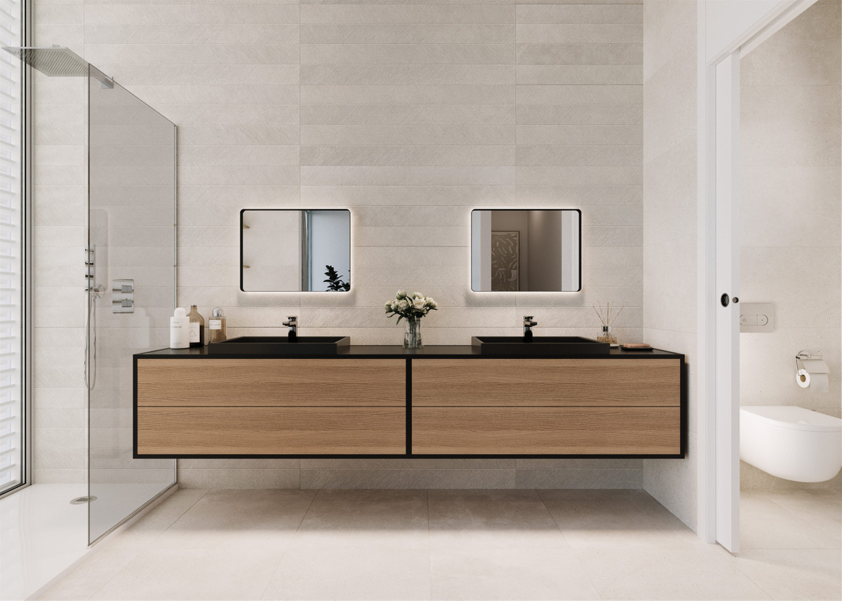 Badeværelsesdesign med bredt træskab, to mørke vaske og to spejle, brusevæg i glas til venstre og et toilet synligt i et separat rum til højre. Billedet bekræfter ikke den valgte boligs præcise badeværelsesfordeling.